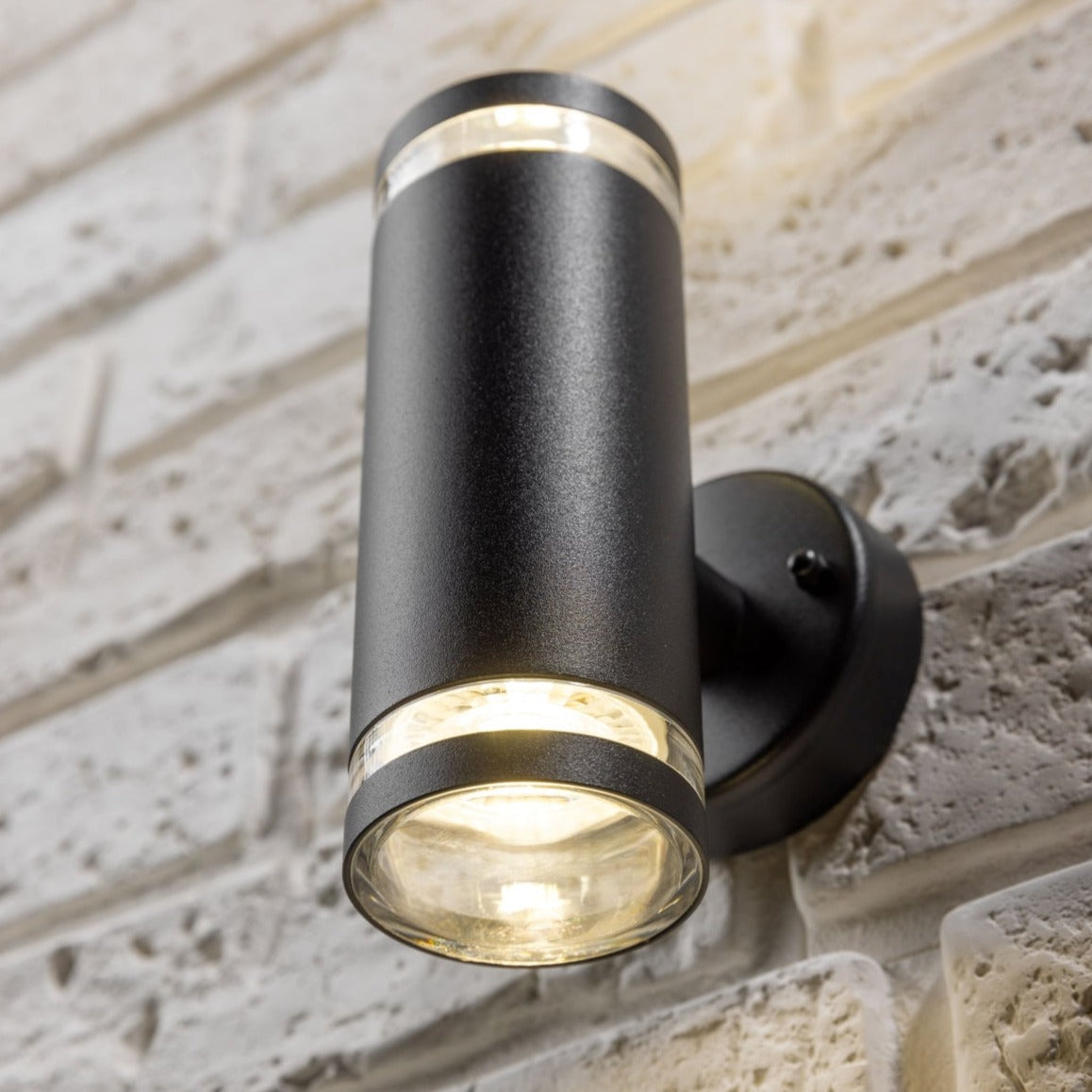 Our Jennifer black outdoor wall mounted up and down cylinder outdoor light would look perfect in a modern or more traditional home design. Outside wall lights can provide atmospheric light in your garden, at the front door or on the terrace as well as a great security solution. It is designed for durability and longevity with its robust material producing a fully weatherproof and water resistant light fitting.