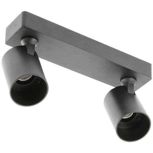 The black Nell twin lamp consists of two cylindrical spotlights, both of which can be tilted and adjusted on their own axis. The spotlights are attached to a rectangular bracket, which makes them equally suitable for mounting on walls and ceilings. Made of an aluminium body and powder coated black, the lamp with its simple design fits well into different spaces.